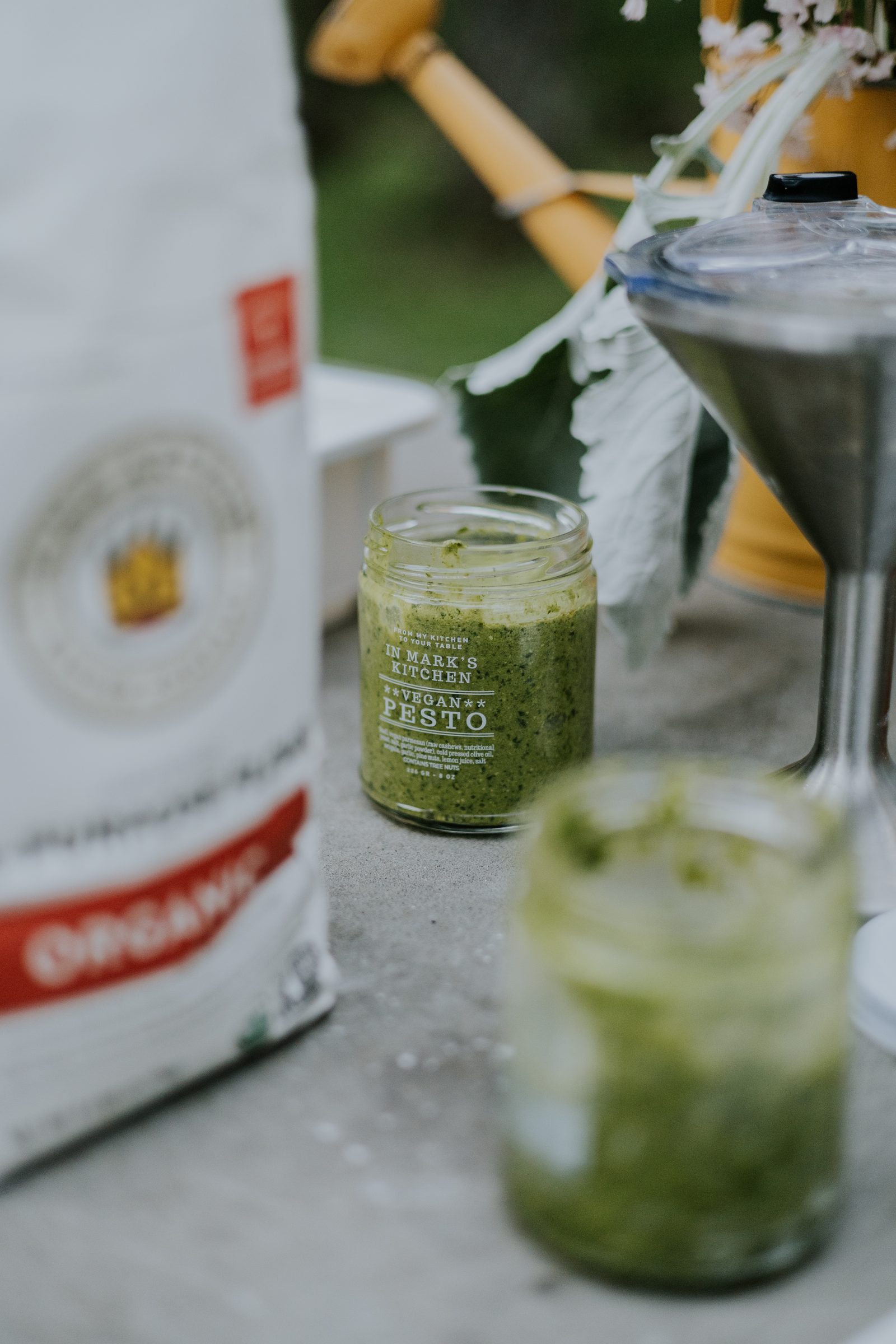 A jar of pesto beside flour and the mixer